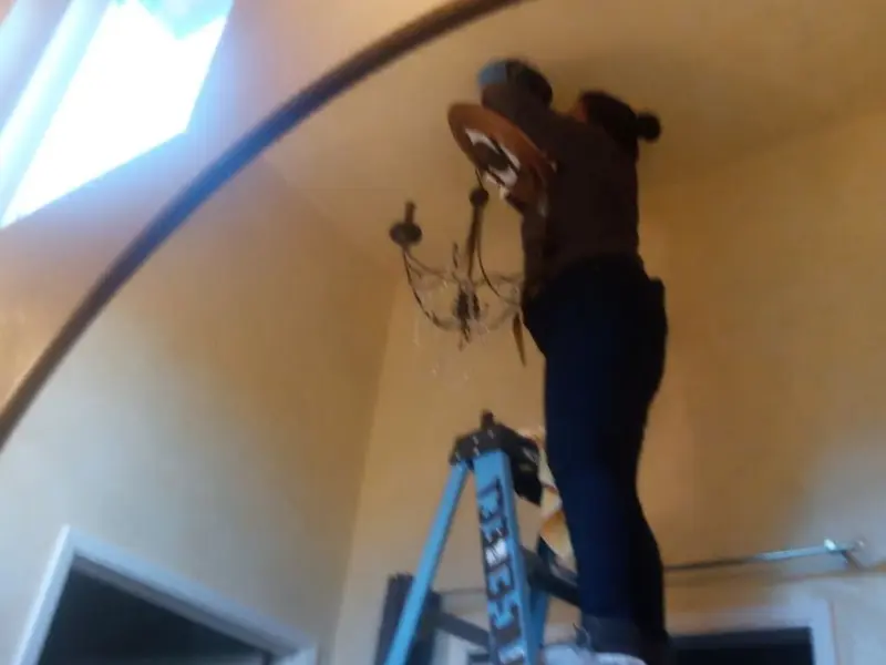 Electrician installing a chandelier in a DeForest residence